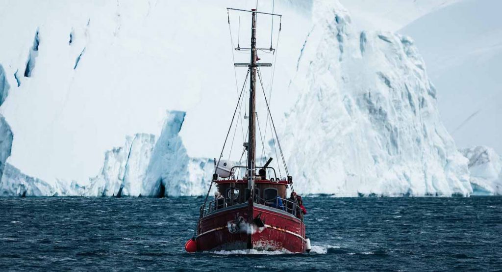 red_boat_in_front_of_gigantic_icebergs