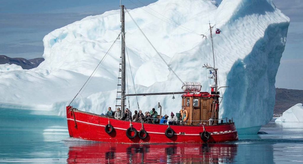Red_Boat_with_visitors_in_front_of_a_gigantic_iceberg